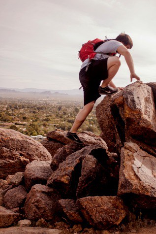 Business Leaders Conquer Fear in 7 Steps depicted with hiker climbing upon a big set of boulders
