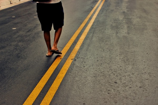Adeventures depicted as man walks the yellow lines in the center of the road.