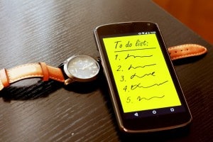 To-Do Lists illustrated by a smartphone with a to-do list on it while it's place along side a watch.