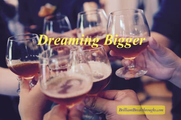 Dreaming Bigger for business success illustrated by people holding up brandy glasses for a celebratory toast